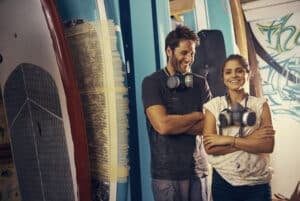 a picture of two people working on surfboards